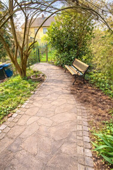 Sonniger Gartenweg mit Bank